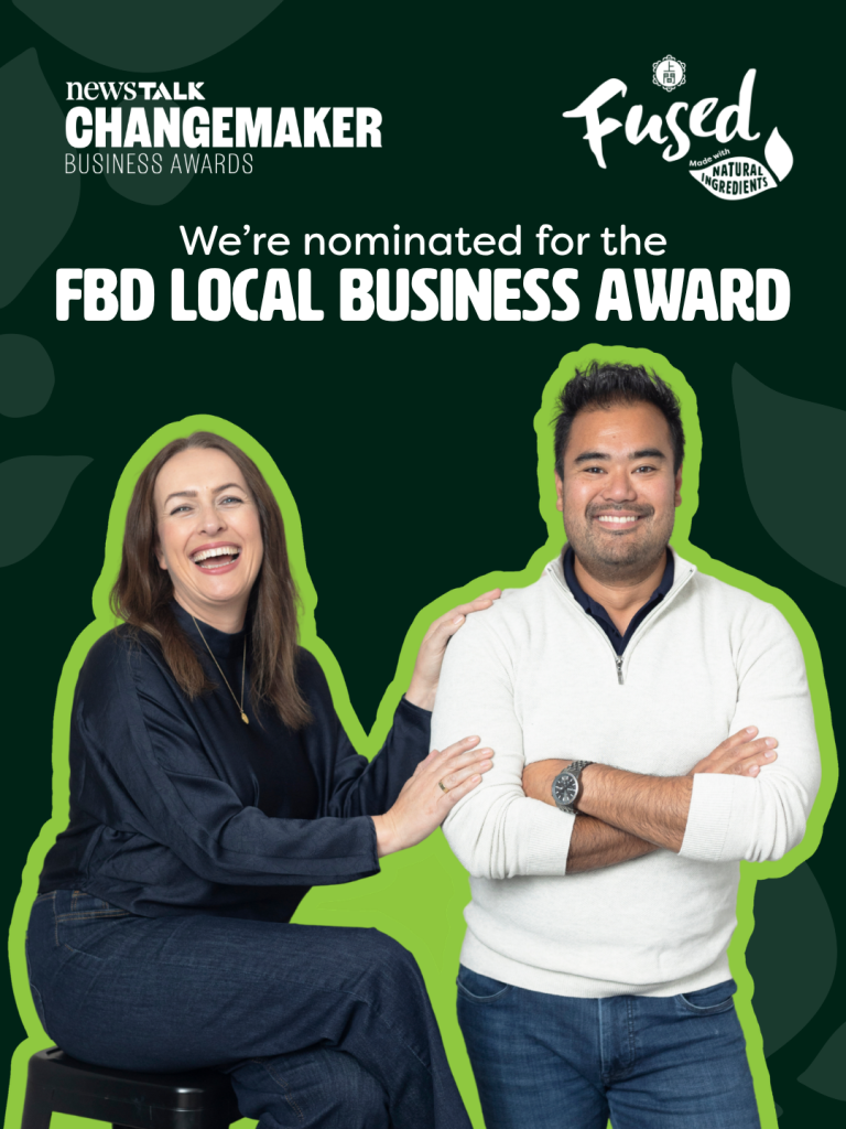 Two people pose in front of a green background with text, "We're nominated for the FBD LOCAL BUSINESS AWARD", with NewsTALK Changemaker Business Awards and a Fused logo visible.